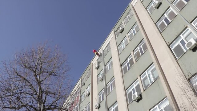 Santa climbing down a hospital roof for a charity event. Santa Claus entering a window.
