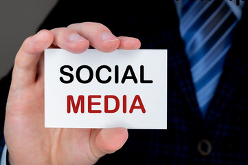 Businessman in suit showing or holding business card with SOCIAL MEDIA text.