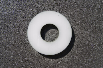 white methacrylate circle with empty center, isolated on black rough background