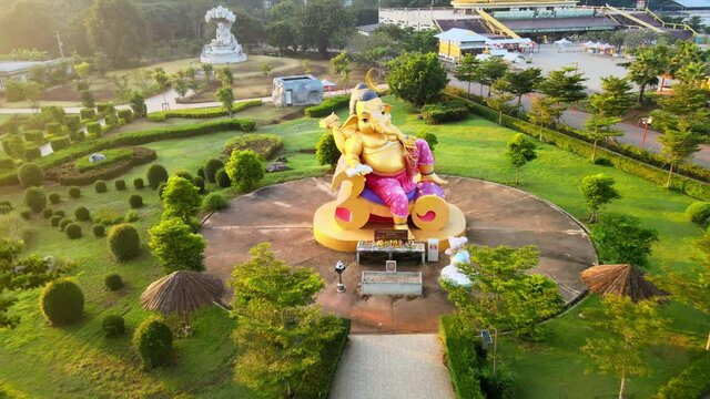 4k Stunning Ganesha. pan up-back an elephant-headed Hindu god of beginnings Ganesh in Khao Yai mountains, Thailand. Sun glares at dawn. left to right. Monk statue of Luang Pu Thuat.
