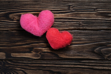 Fototapeta na wymiar Two woolen handmade hearts on the dark brown wooden boards
