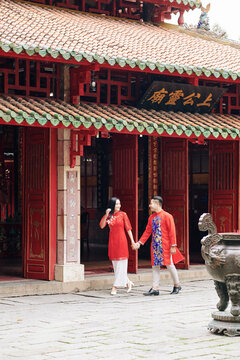 Happy Just Married Asian Couple In Traditional Clothes Holding Hands When Walking Outdoors In Old City