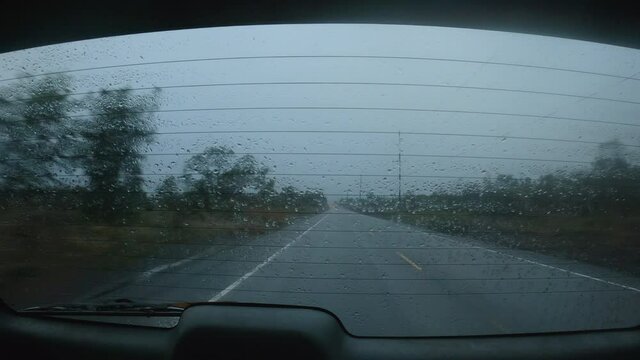 Wet and foggy road races by from the rear view window of a moving vehicle. Captured in Hawaii. 4K.