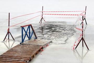 Empty ice hole with wooden planked pathway boardwalk and fence on a Sunny frosty winter day, winter...