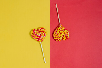 Striped heart shaped lollypops on the yellow-red background. Sweet candy. Valentine's day. Heart shaped lollypops.