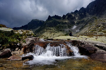 Obraz na płótnie Canvas Small waterfall in a mountainous rocky surroundings on a cloudy day in the High Tatras mountains in Slovakia