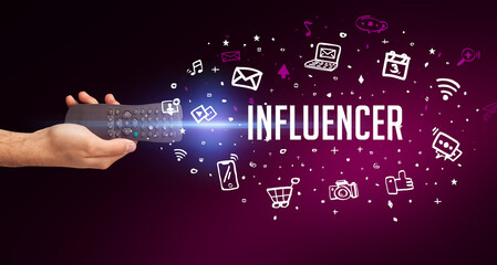 hand holding wireless peripheral with INFLUENCER inscription, social media concept