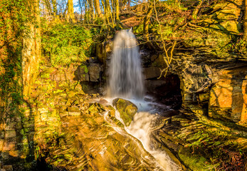 A long exposure view of water cascading over a top-level waterfall at Lumsdale on Bentley Brook, Derbyshire, UK