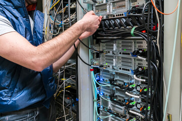 There is a close-up of the switching of Internet communication wires. Technical work in the data center server room. Maintenance of computer equipment on the hosting site