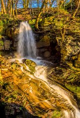 Fototapeta na wymiar A long exposure panorama view of water cascading over a top-level waterfall at Lumsdale on Bentley Brook, Derbyshire, UK