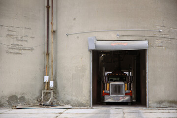A semi truck pulls into a concrete silo.  © Abject