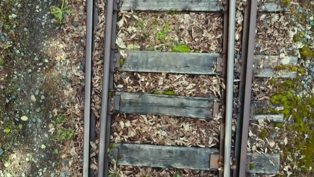 Straight down drone view moving along abandoned rail tracks.
