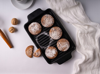 Cookies, sprinkled with powdered sugar, in a cast iron pan with a white cloth. On white background.