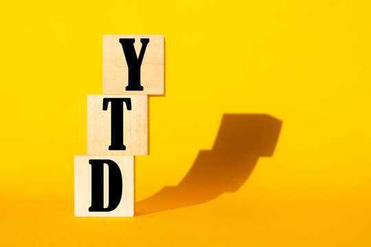 YTD symbol. Word YTD - year-to-date on cubes on a beautiful wooden table, white background. Business and YTD concept.