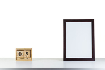 Wooden calendar 05 January with frame for photo on white table and background