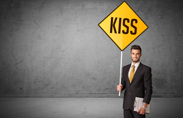 Young business person holding road sign with KISS inscription, new rules concept
