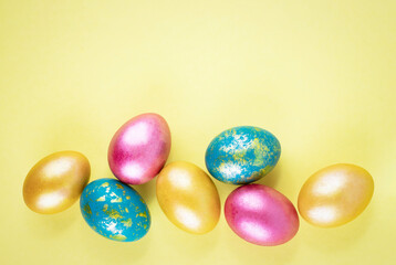 Fototapeta na wymiar Bright gold and multi-colored colored eggs on a yellow background. Easter theme, holiday. Happy easter card with copy space for text in minimalist easter style. Yellow, gold. Happy Easter