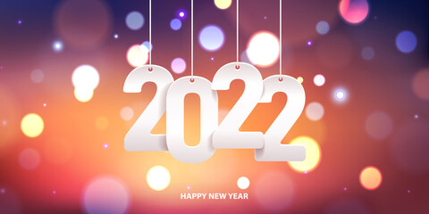 Happy new year 2022. Hanging white paper number on a colorful blurry background.
