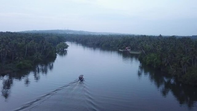 Boat Cruising In Rippled Backwaters Of Poovar With Lush Green Vegetation And Coconut Trees Lined Up On The Shores In Kerala, India - aerial drone shot