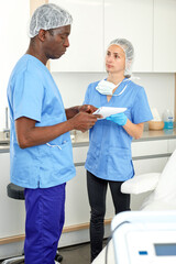 Professional cosmeticians woman and man having conversation before procedure in clinic of esthetic cosmetology