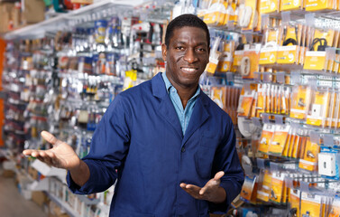 Happy African American man offering for sale different supplies for renovation works in building...