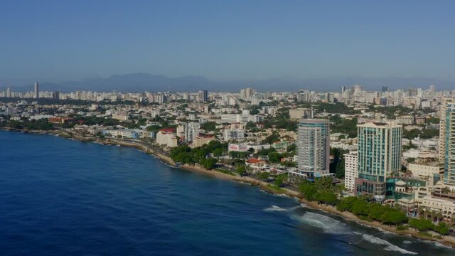 Waterfront Hotel Buildings Along Malecon Esplanade With Cityscape Of Santo Domingo, Dominican Republic. - aerial