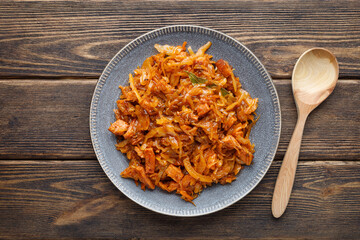 Stewed or braised cabbage in a plate on a wooden table.