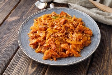 Stewed or braised cabbage in a plate on a wooden table.