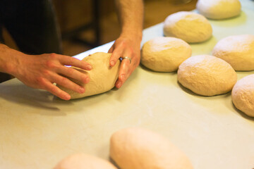 The baker forms a loaf of bread from the dough.