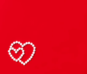two hearts made of round white pills on a red background, minimalism. copy space