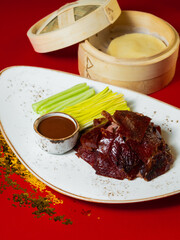 Chinese national dish Peking duck. The meat is cut into pieces, flakes in a wooden box. Standing on a red background, golden fishing lines are scattered nearby. Chinese New Year. Asian food.