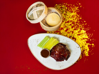 Chinese national dish Peking duck. The meat is cut into pieces, flakes in a wooden box. Standing on a red background, golden fishing lines are scattered nearby. Chinese New Year. Asian food.