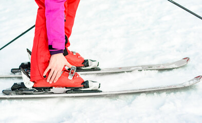 Sport set of skis, boots and sticks in red on woman's leg close up.