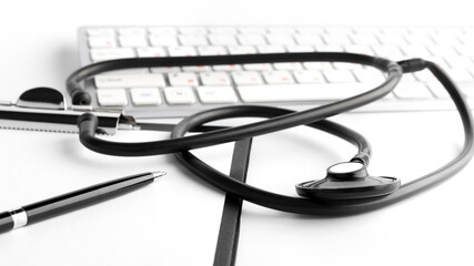 Stethoscope, pen, clipboard and keyboard on white background. Medical concept. Closeup.