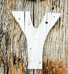 Cracked old weared down painted letter Y, nailed to an crumbling wooden board wall. Rustic captures.