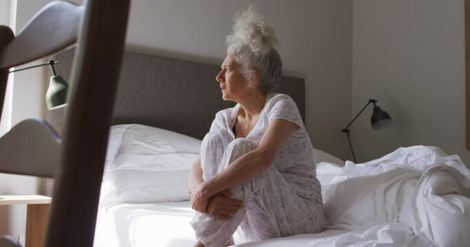 Senior caucasian woman sitting on the bed at home