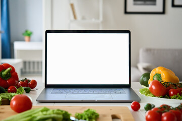 Laptop computer with mockup white screen on vegetarian healthy food vegetable background. Online...