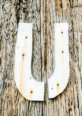 Split in two old weared down painted letter U, nailed to an crumbling wooden board wall. Rustic...