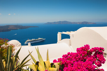 Fototapeta na wymiar White architecture on Santorini island, Greece. Flowers on the terrace with sea view. Travel destinations concept