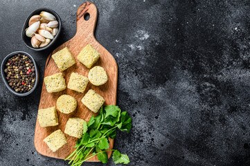 Raw falafel balls on a wooden cutting board. Black background. Top view. Copy space