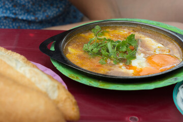 Vietnamese street food breakfast: fried eggs dish with a fresh French baguette. Hoi An, Vietnam