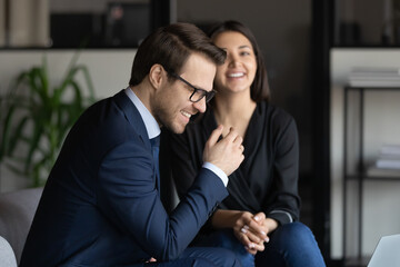 Close up happy diverse colleagues chatting, excited businessman wearing glasses and Indian businesswoman laughing at joke, discussing funny news, employees having fun during break in modern office