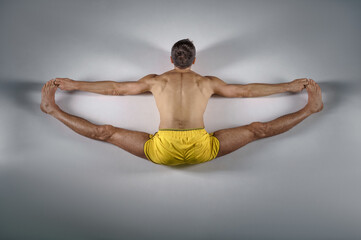 Male yoga sits on a twine, top view