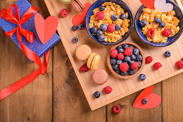Two portions Muesli with berries and sweet pastries for a romantic breakfast. A surprise for dad on father's day or for mom. High quality photo. Copy space. Above