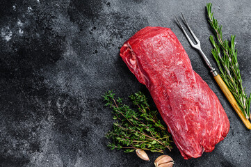 Raw fillet Tenderloin beef meat for steaks with thyme and rosemary. Black background. Top view....