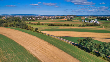 Fototapeta na wymiar Aerial View of Multiple Farms and Train Tracks going Thru Them on a Beautiful Summer Day