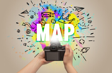 Close-up of a hand holding digital camera with abstract drawing and MAP inscription
