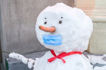 A portrait of a snowman in a medical mask. Winter concept of quarantine restrictions. The snowman...