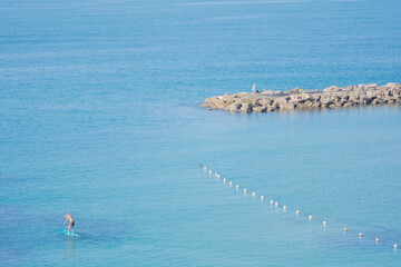 Man surfing on a SUP (Standup paddleboarding) in the water of the Mediterranean Sea, Tel Aviv,...