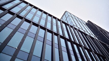 Facade of a modern office building during snowfall from the bottom up